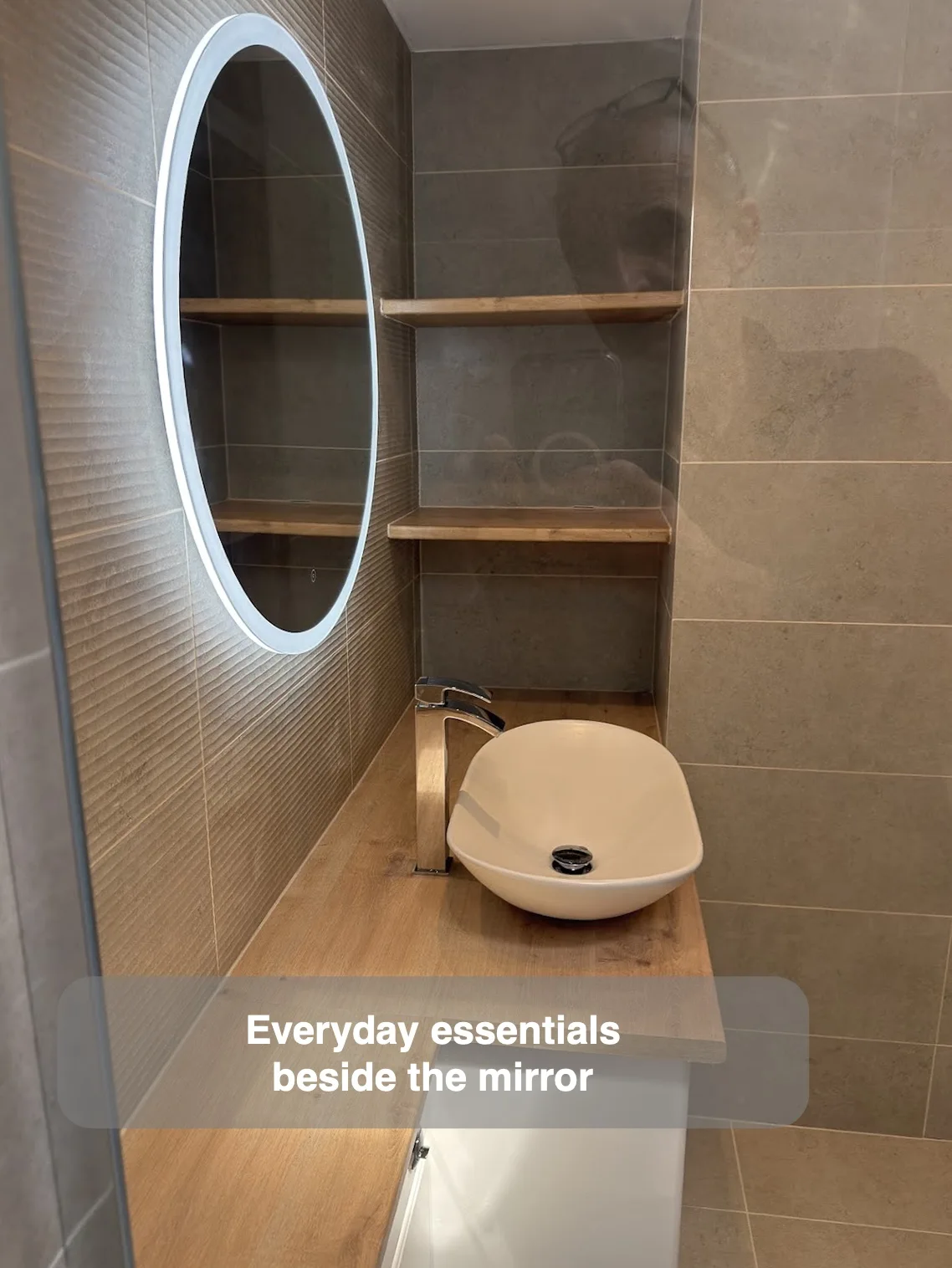Two timber shelves beside an oval mirror in a narrow basin alcove