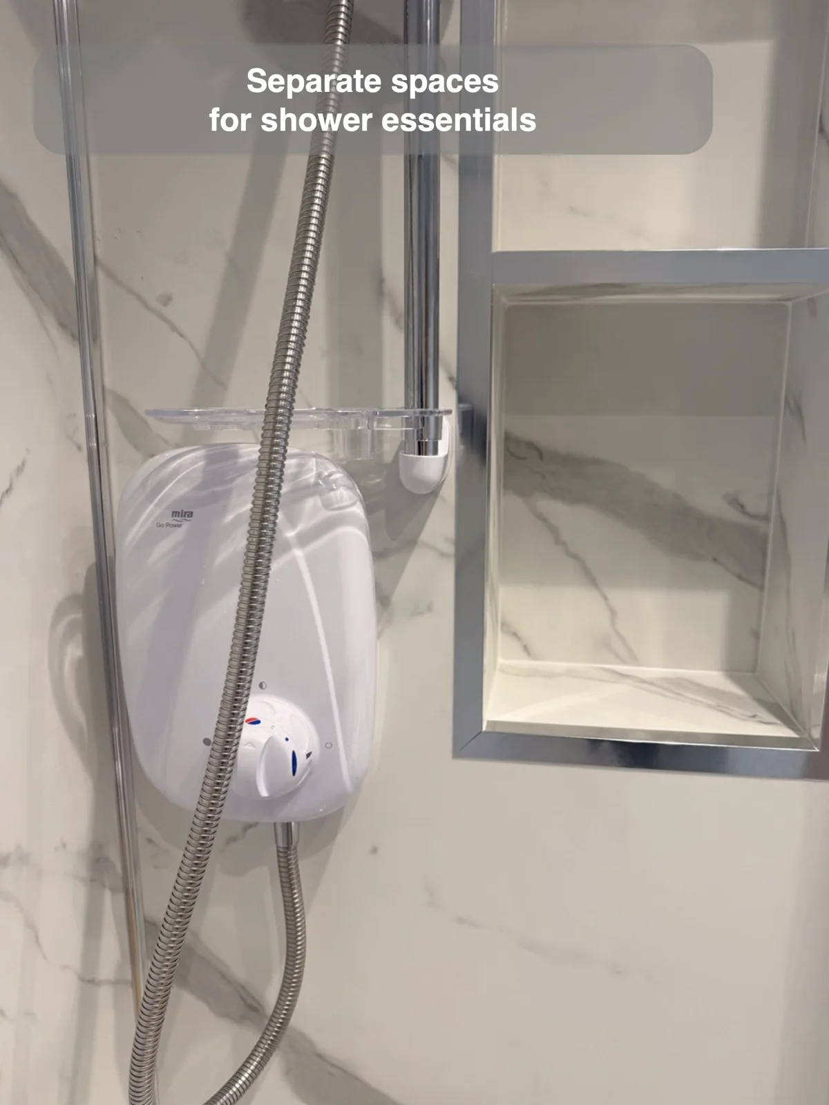 Two vertically stacked rectangular recesses with silver borders beside a white shower unit and chrome hose.