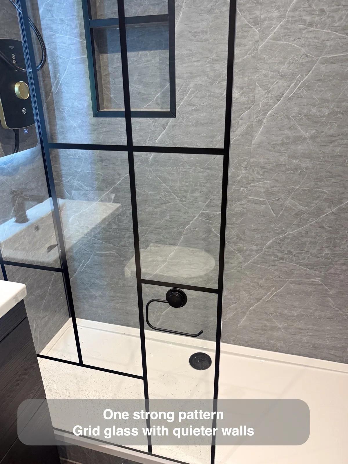 Black grid shower screen against subdued grey walls.