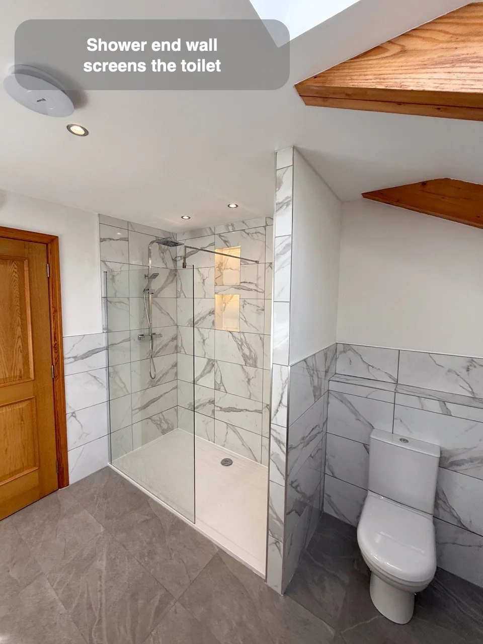 Use the shower end wall to screen the toilet from view