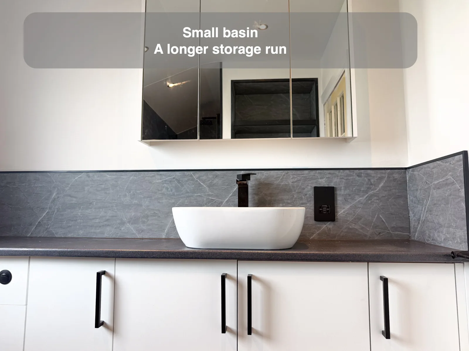 White vessel basin on a long worktop above white cupboards.
