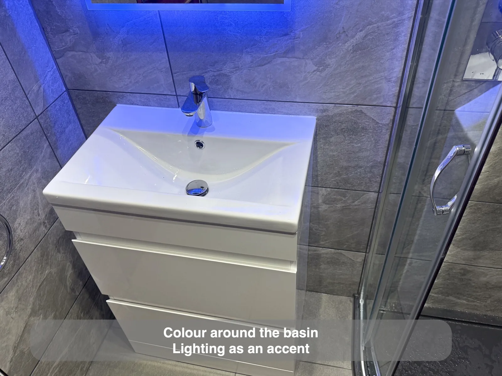 White vanity with blue illumination against grey cloakroom walls.