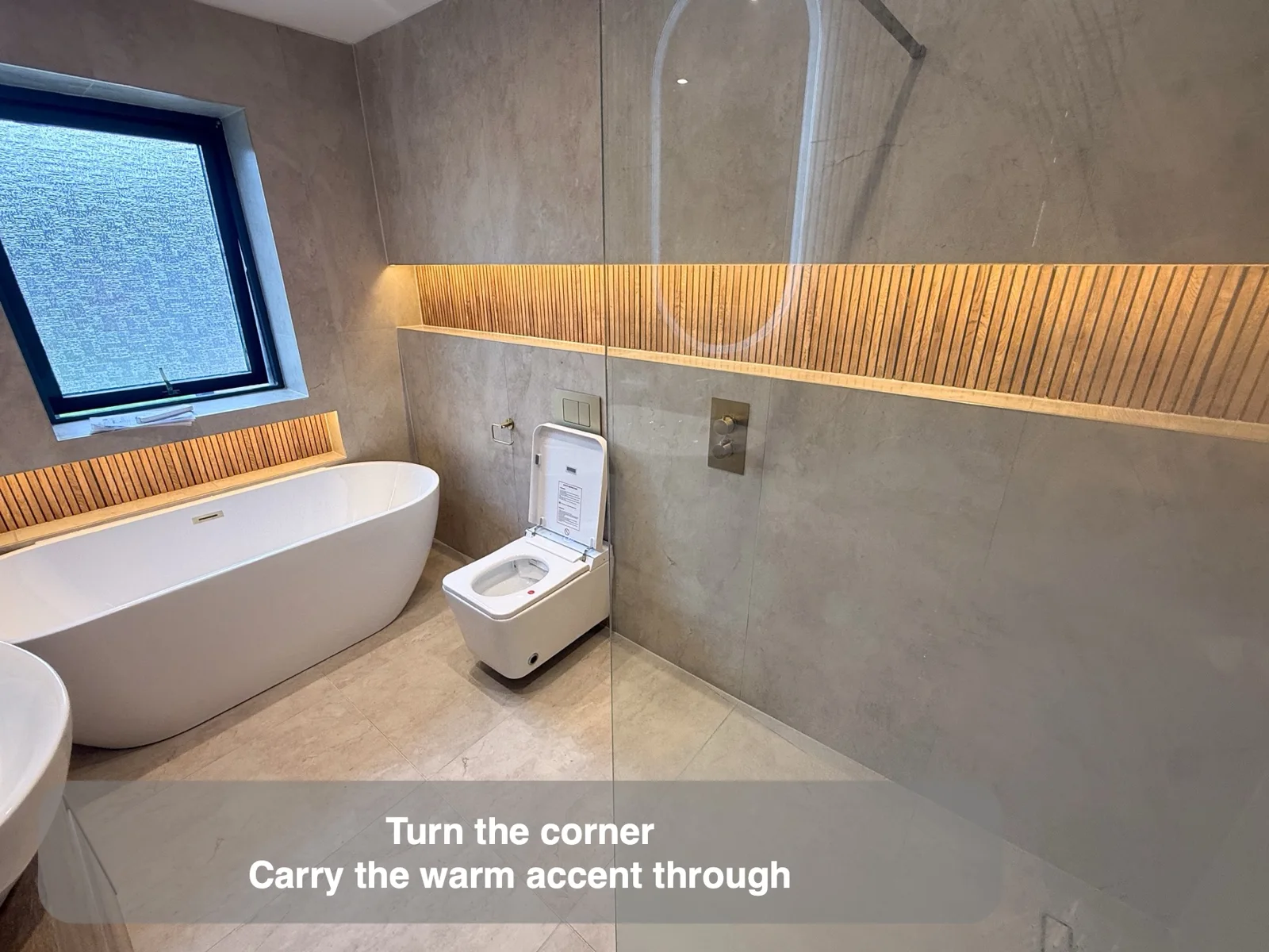 Freestanding bath with warm vertical wall detail and adjacent long recess.