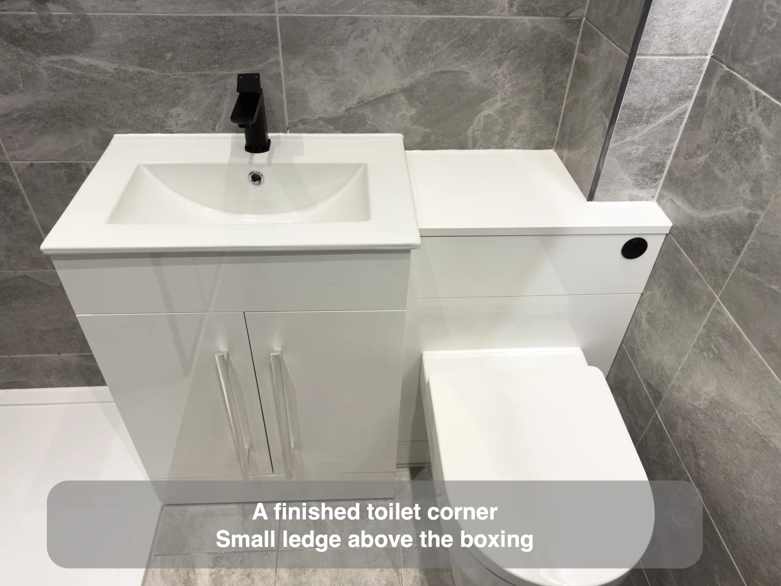 Floor-standing basin cabinet beside toilet casing with a narrow ledge.