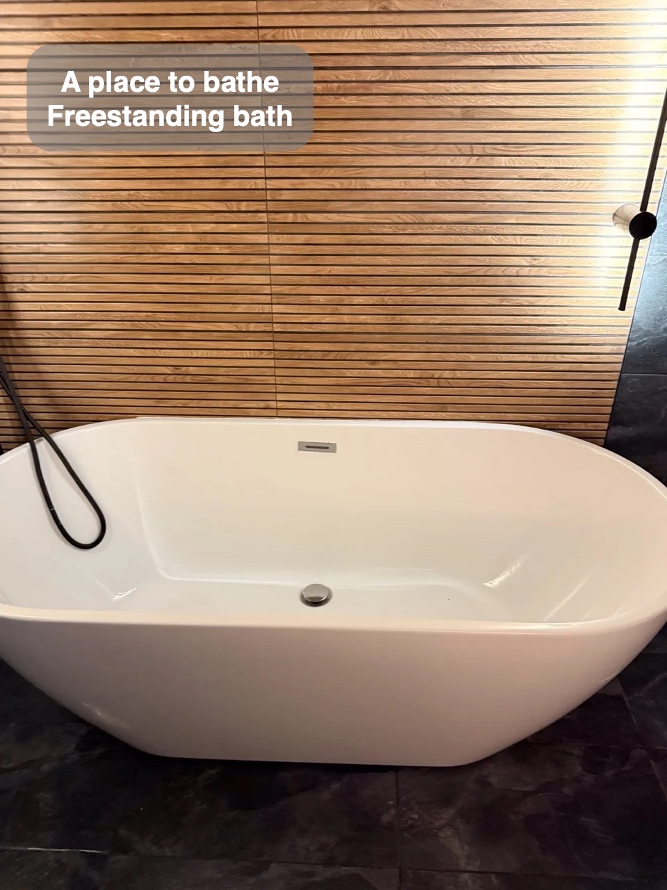 Freestanding bath against wood-effect tiled wall